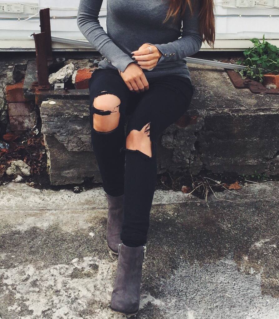 A fashion blogegr wearing black ripped jeans and grey boots 