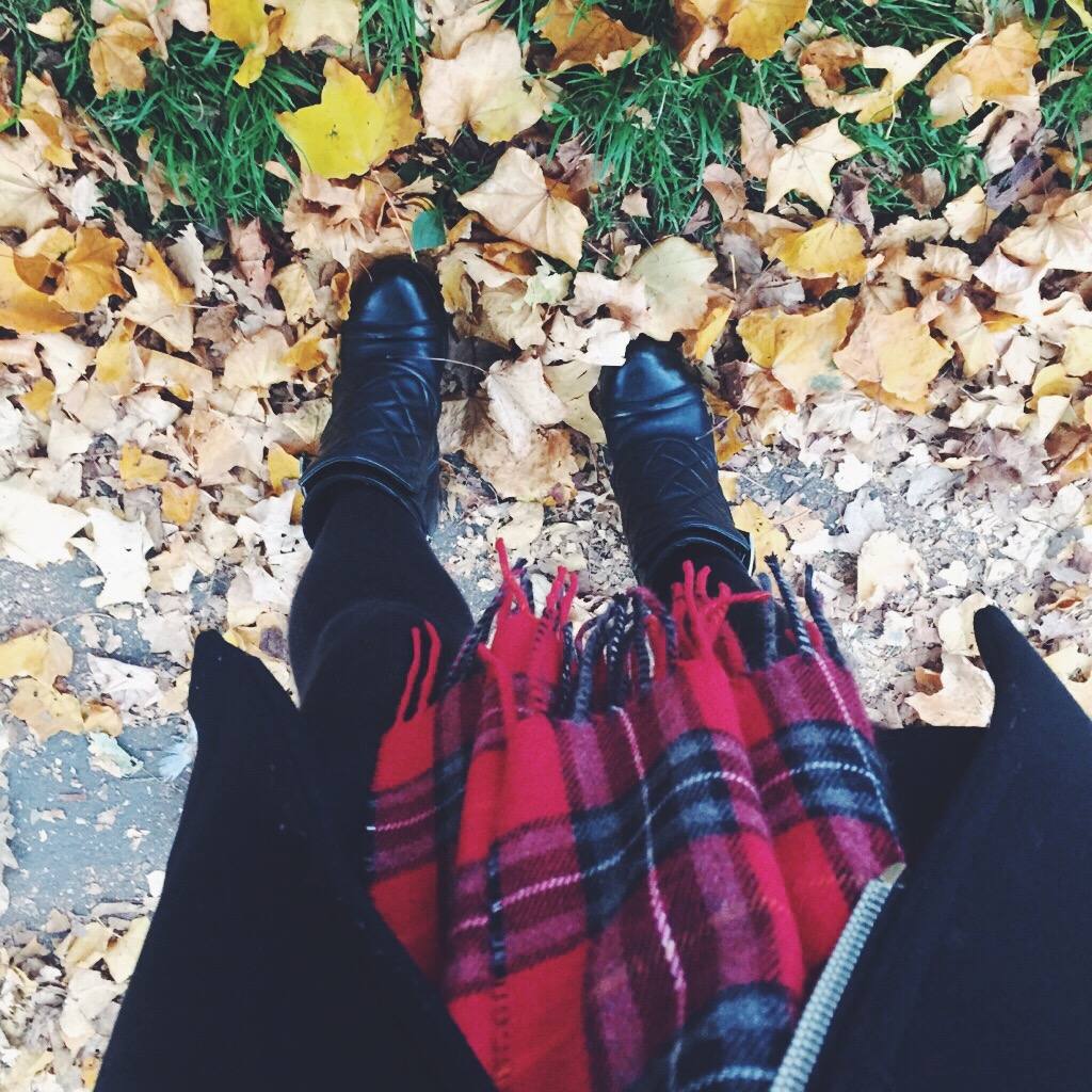A fashion blogger wearing a red tartan scarf in the park 
