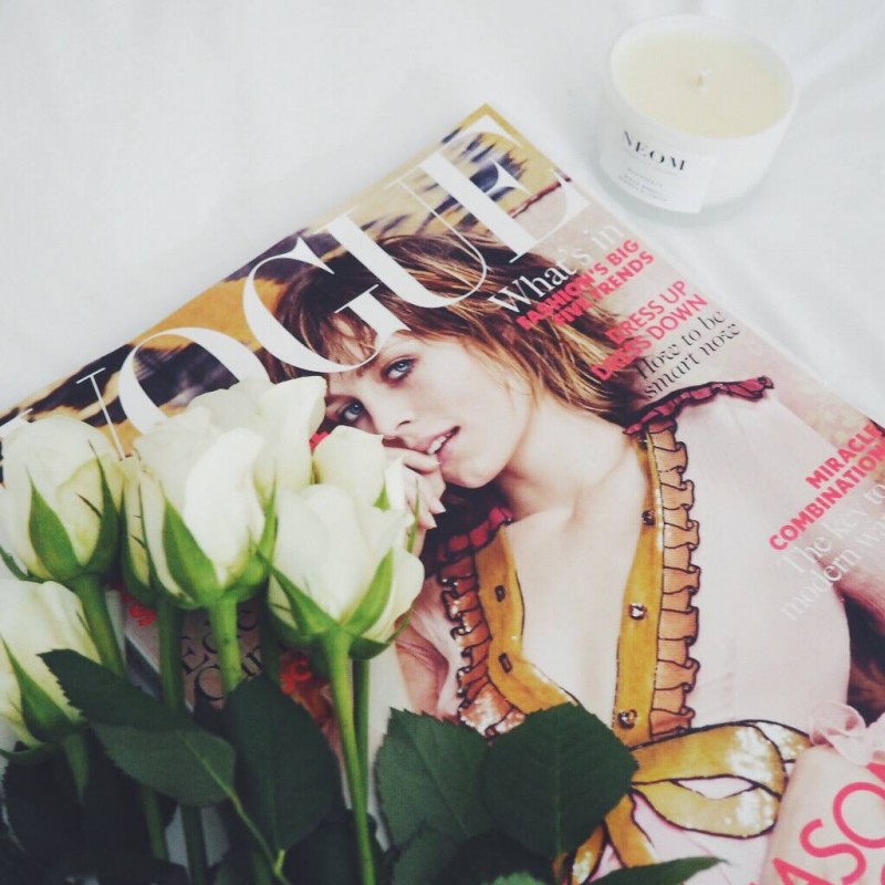 A picture of Vogue magazine, white roses and a Neom candle